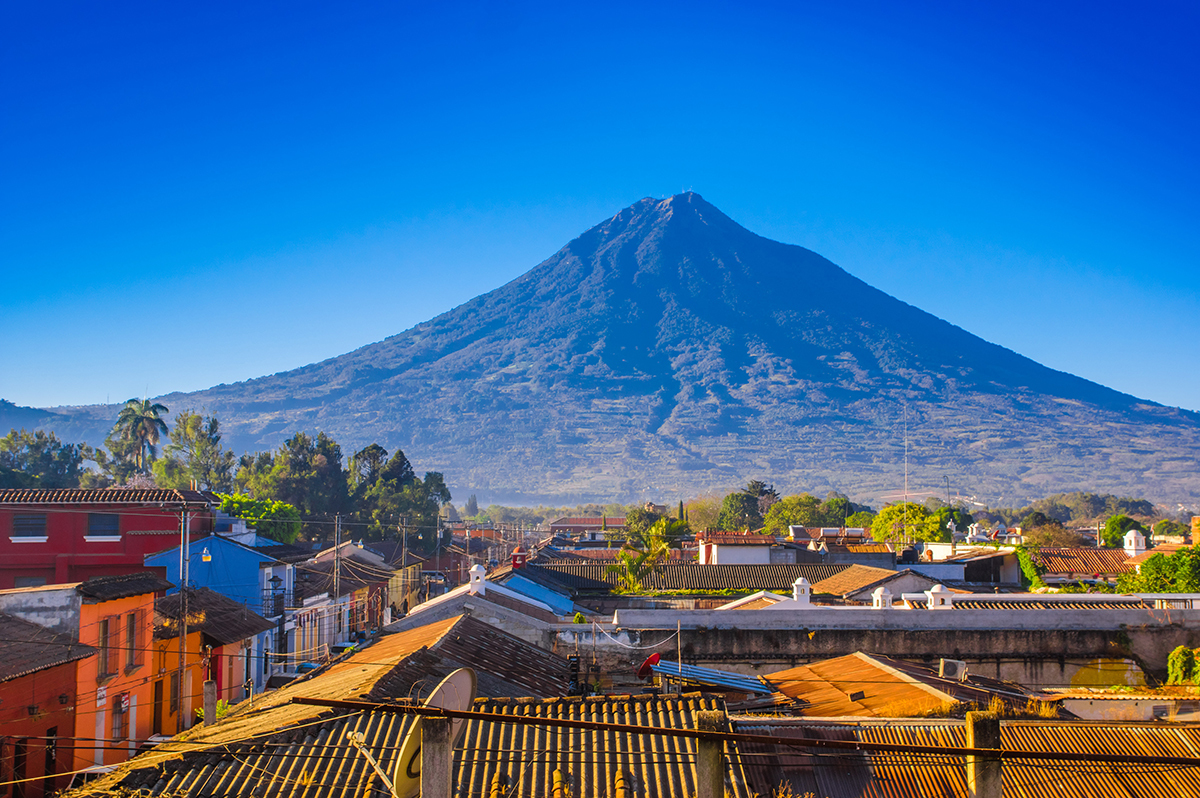 Beautiful outdoor view of rooftops of the building in Antigua city with agua volcano mountain behind in a beautiful sunny day and blue sky